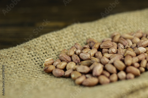 Raw peanuts on a rough cloth and wooden background