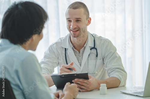 Doctor listening patient explain his symptom and notes to medical record.