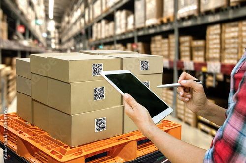 Industrial 4.0 , Augmented reality and smart logistic concept. Hand holding tablet with AR application for check order pick time around the world and supply chain in smart factory background. photo