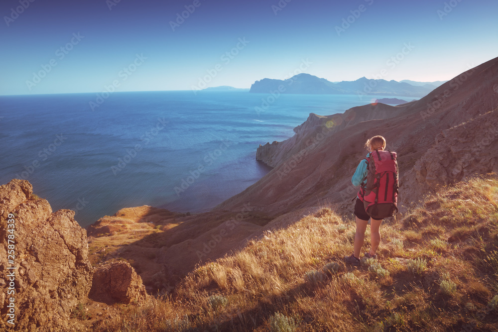 Girl hiker above the sea at sunset