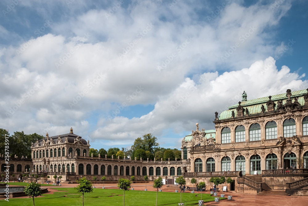 View of the square in Zwinger gallery from steps of Old Masters Picture Gallery towards French and Rampant pavilions at Dresden, Saxony, Germany against astonishing clouds in blue sky