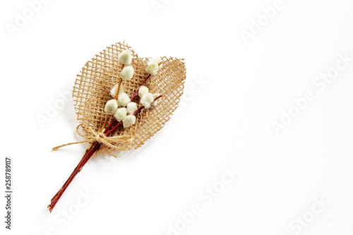 Schilderij op canvas Decorative bouquet of twigs of blossoming willow and leaves of coarse jute fabric on white background