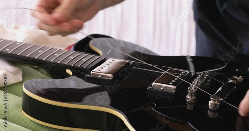 DIY, guitar maintenance, setting up strings at  vintage  style semihollow body electric guitar photo