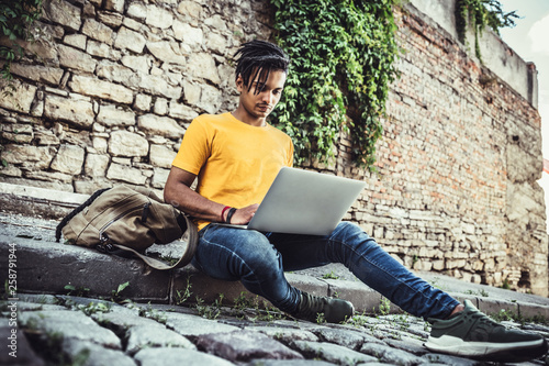 Young slylish man work in laptop outdoors. The concept of study, freelancing, work, technology. photo