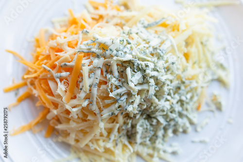 Many different cheeses grated and shredded on a white plate