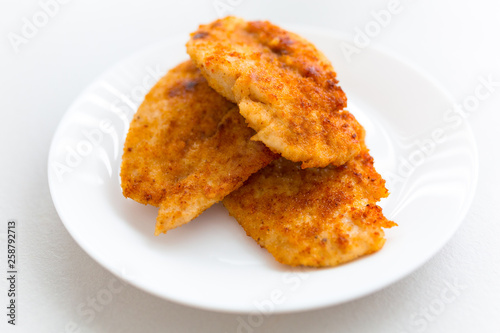 Bread crumb coated fried chicken breast on a white plate