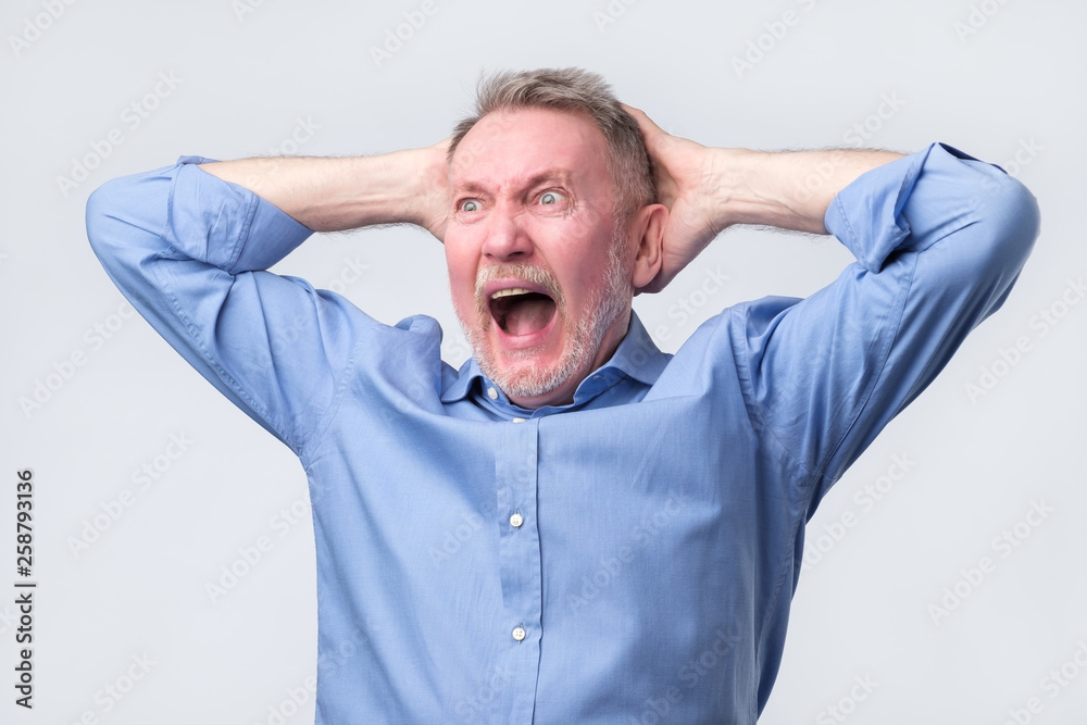Senior man with angry grimace on his face,with mouth opened in shout Senior man with angry grimace on his face,with mouth opened in shout