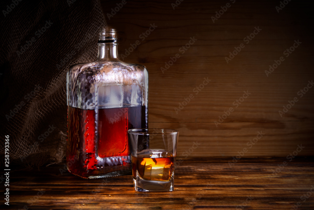 glass with alcohol drink and bottle on wooden background glass with alcohol drink and bottle on wooden background