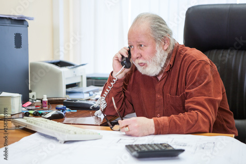 Executive senior businessman using telephone, talking wih somebody while working in the office