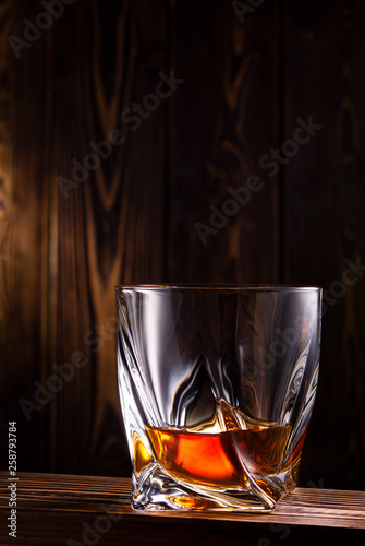 glass of whiskey or cognac over wooden background