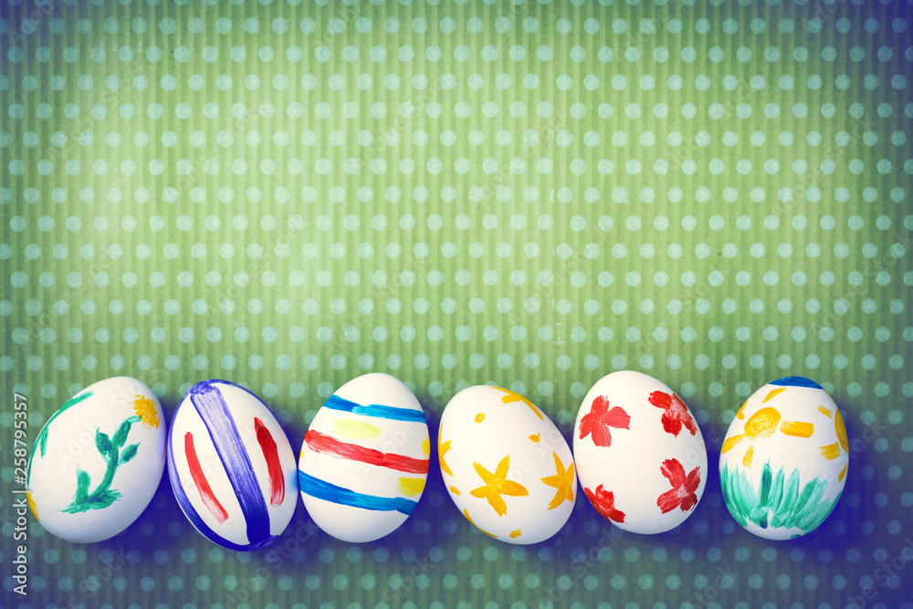 Fototapeta premium Painted Easter eggs on a green background with white polka dots. Toned image. Beautiful holiday card. Space for text. Happy easter.