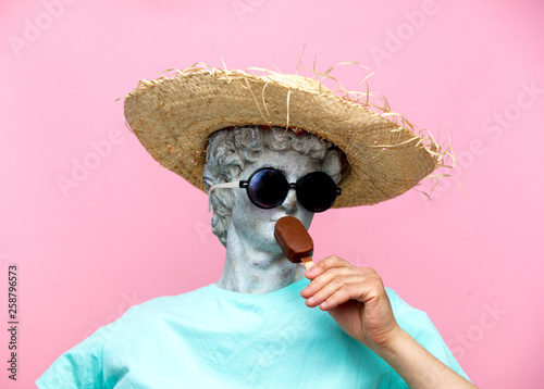 Photo Antique bust of male in hat with ice-cream on pink background.