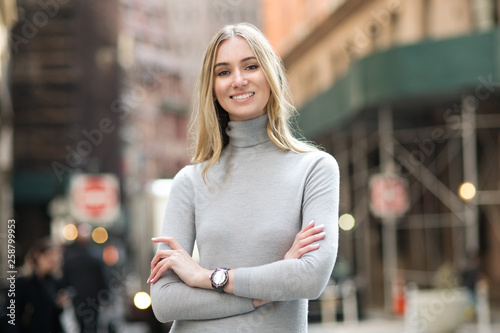 Beautiful smiling businesswoman with arms crossed standing outdoors on city street