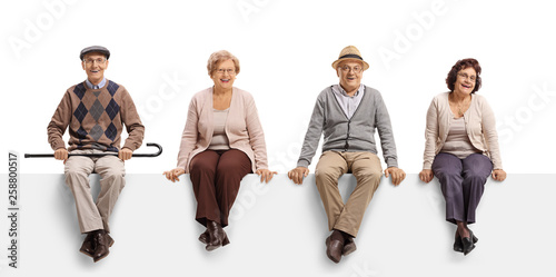 Two senior men and two senior women sitting on a white panel and posing photo