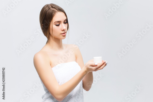 Beauty portrait of half-naked pretty woman looking on cream on her palm isolated over white background copy space
