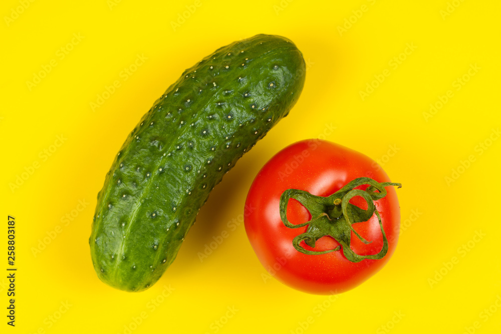 Beautiful fresh cucumber and tomato on yellow background. Ripe vegetables Beautiful fresh cucumber and tomato on yellow background. Ripe vegetables
