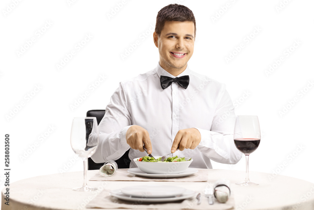 Handsome man eating a salad at a restaurant table and smiling at the camera Handsome man eating a salad at a restaurant table and smiling at the camera