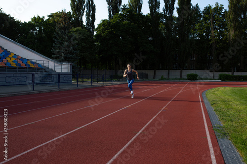 Fitness woman running at the empty stadium at the evening