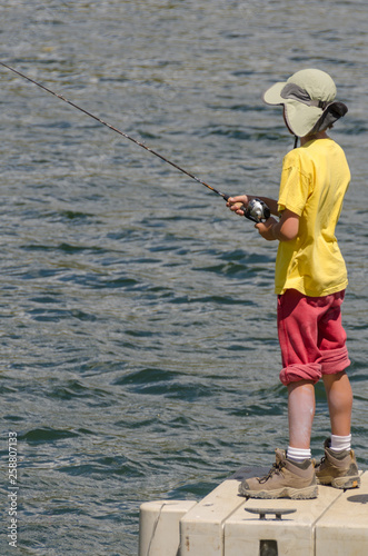 Child Fishing Off of Dock on Lake