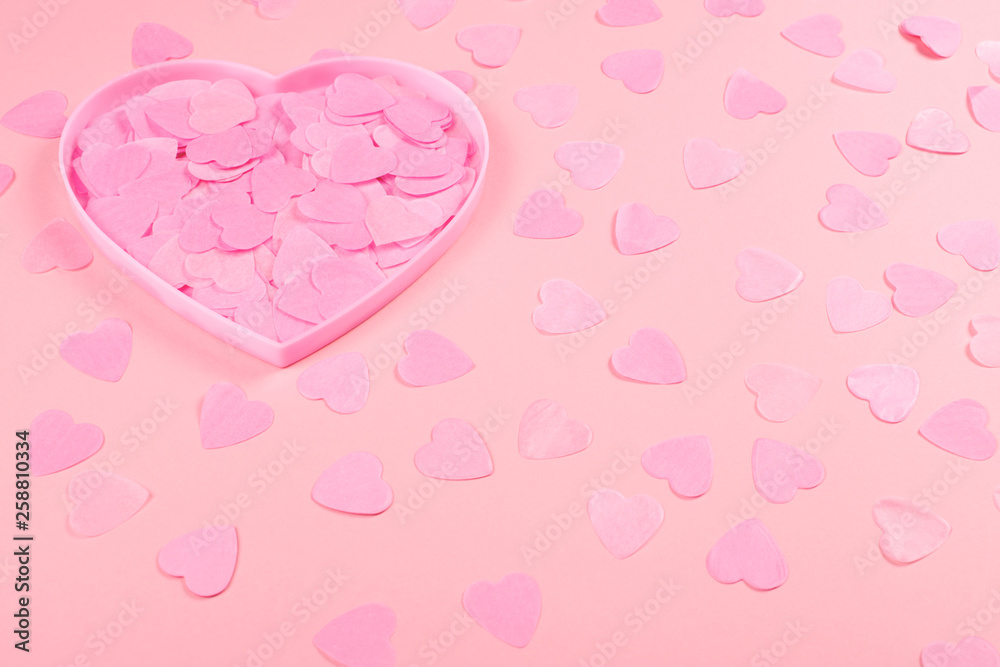 Pink heart-shaped box full of confetti hearts.