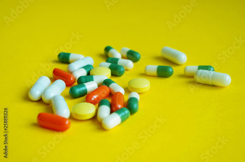 Colorful pills on yellow background.Pharmacy theme, health care, drug prescription for treatment medication and pharmaceutical medicament