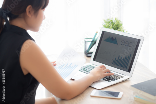 Beautiful asian woman working and typing with laptop computer at office  businesswoman looking graph diagram analysis statistic data of finance  girl using notebook  profit growth  business concept.