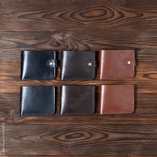 Six handmade leather wallets on wooden textured background. Up to down view. Wallet stock photo.
