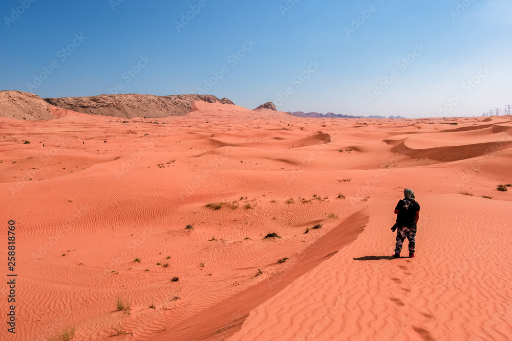 A photographer standing in the sand dune in the arabian desert A photographer standing in the sand dune in the arabian desert