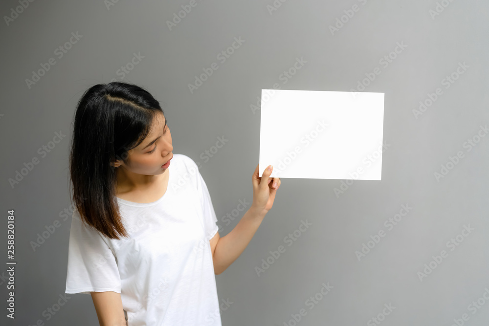 Young woman holding a blank poster for text on a white background.