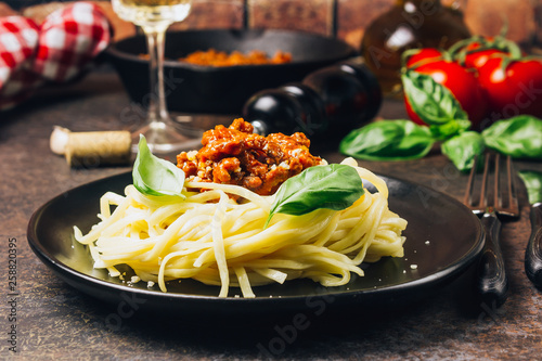 tagliatelle pasta with bolognese sauce and parmesan cheese in black plate