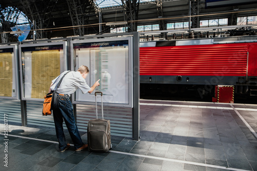 Foto Pendler - Person auf der Reise am Gleis am Bahnhof unf schaut nach Informationen