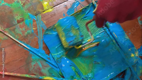 Paint roller rolls through blue green plaint