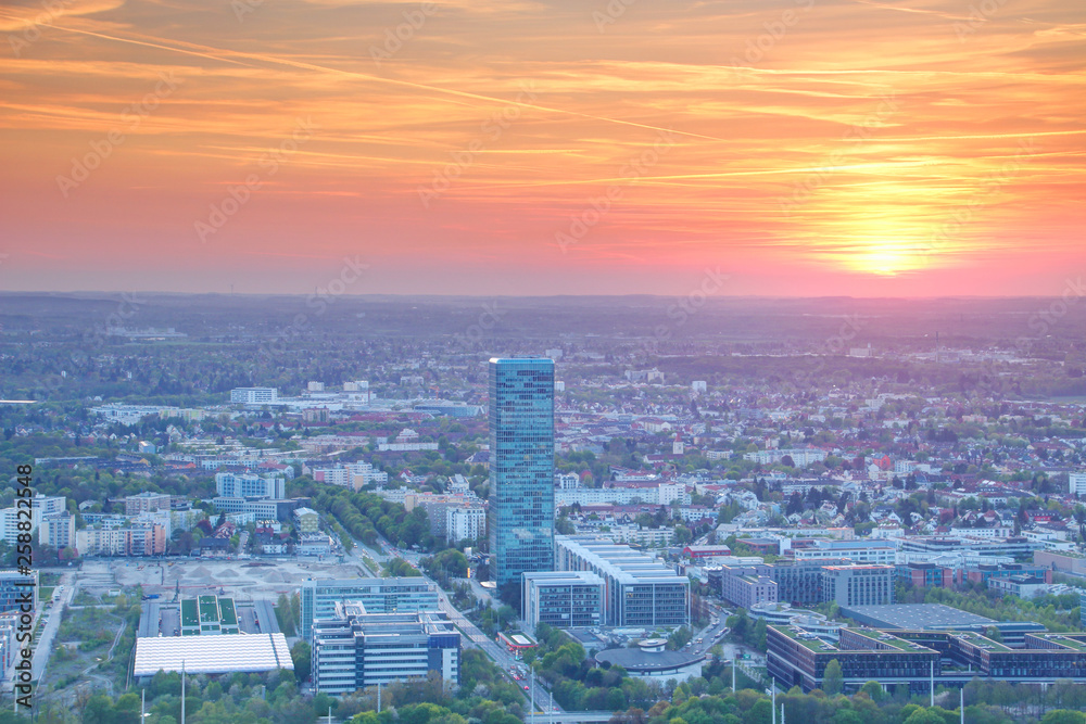 Elevated view of modern European city commercial / business district at sunset with glass and concrete office buildings, high tower blocks in outskirts under orange sky, Moosach Munchen Germany Europe