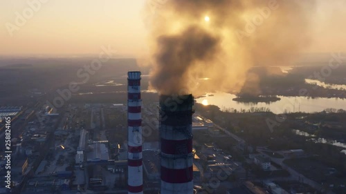 Aerial circling view of smoking chimneys of CHP plant (coal-fired power station) at sunset photo