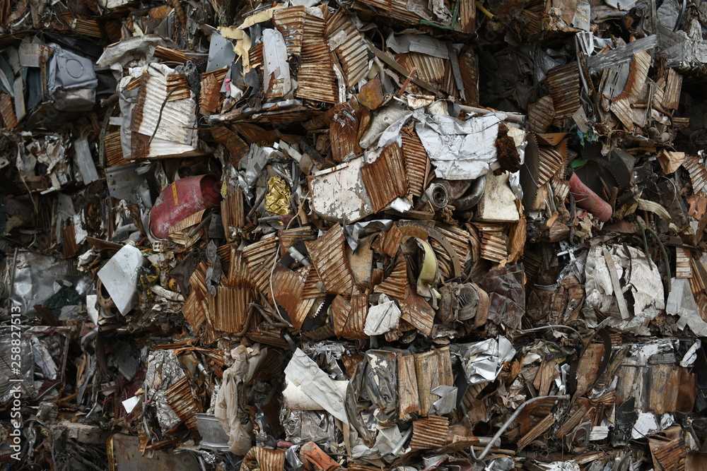 Large stack of crushed, compressed cubes or blocks of discarded iron metals for scrap metal recycling.