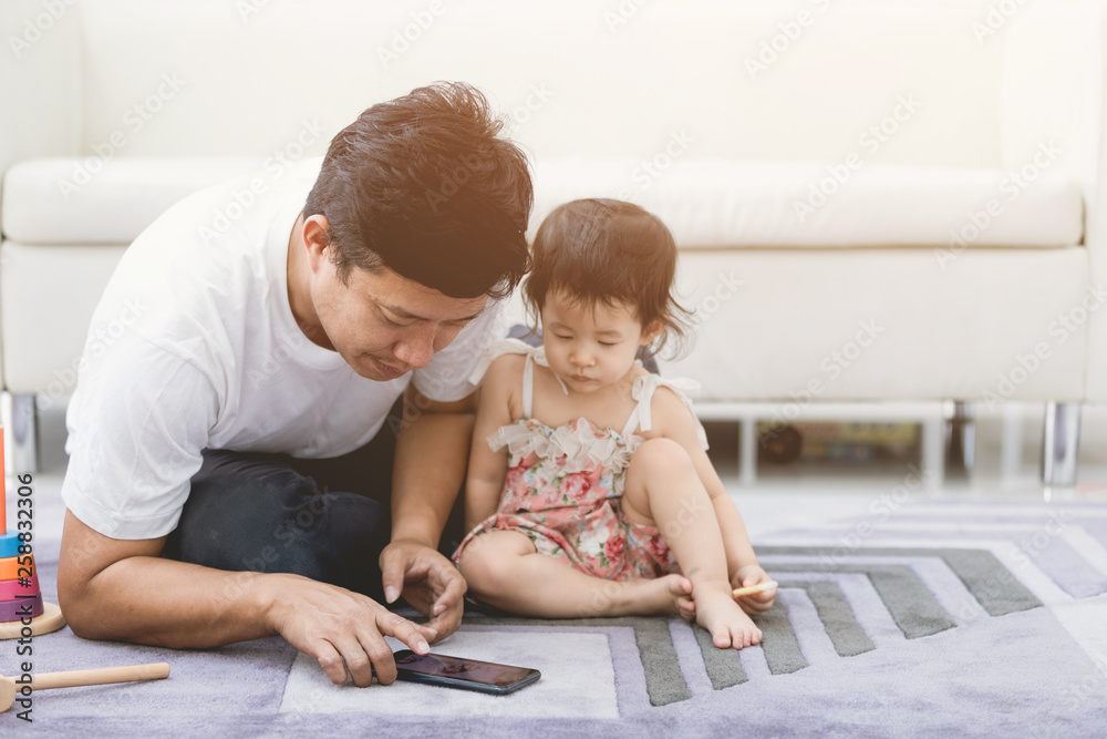 VIew of a Father and his little daughter using mobile at home . VIew of a Father and his little daughter using mobile at home .