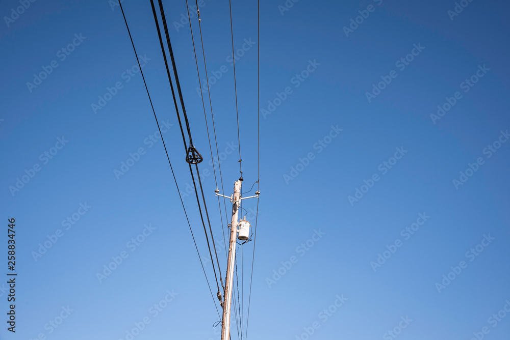 Electric poles with wires and cables set on a bright blue daylight sky. Electric poles with wires and cables set on a bright blue daylight sky.