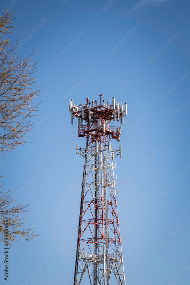 A tall metal cellular tower with a tree set on a clear blue sky background. A tall metal cellular tower with a tree set on a clear blue sky background.