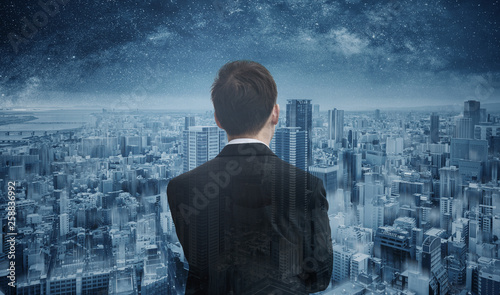 Businessman looking to futuristic blue city with starry sky. Smart business, business vision and futuristic business technology