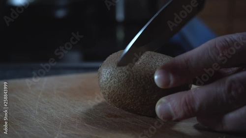 Cutting a kiwi fruit on a wooden chopping board photo