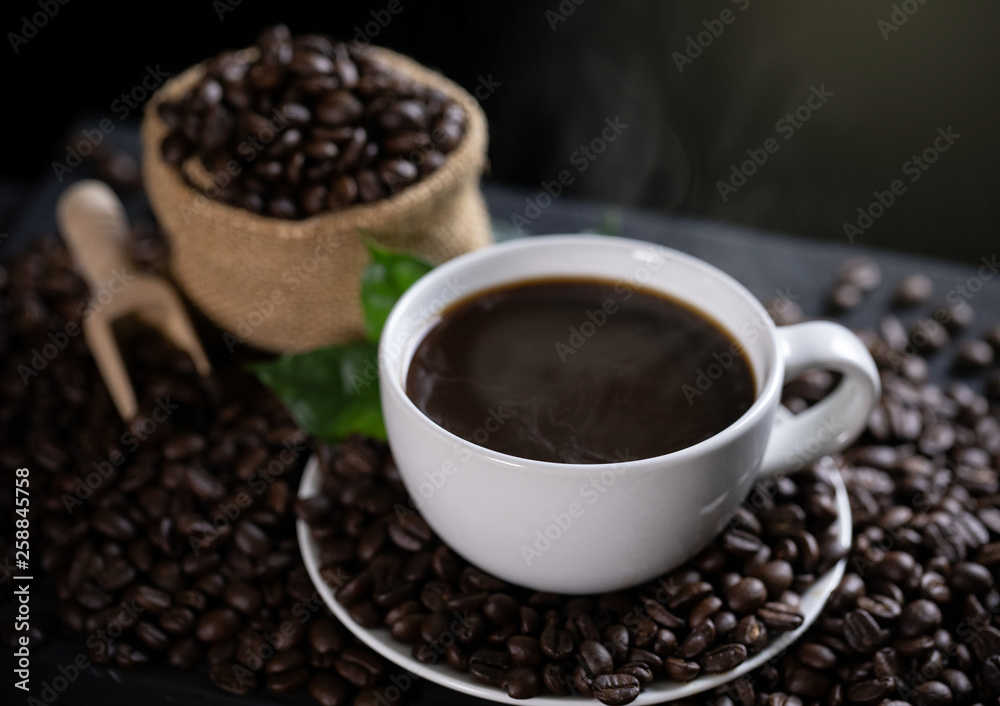 Hot coffee cup with coffee beans on the wooden table Hot coffee cup with coffee beans on the wooden table