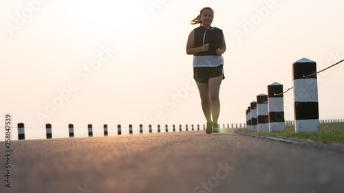 Overweight Asian women jogging in the street in the early morning sunlight. concept of losing weight with exercise. with copy space.