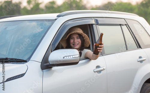 A beautiful woman holding a drink bottle extending out of the car © sunti