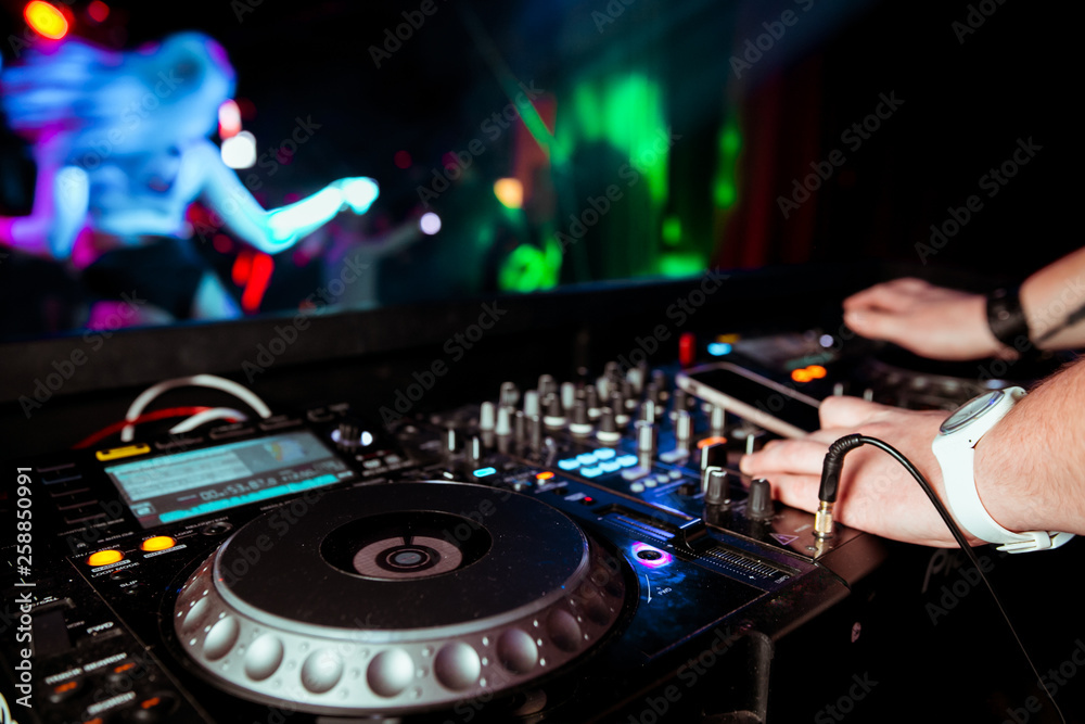 Obraz premium DJ remote on stage at the nightclub. background of dancing people.
