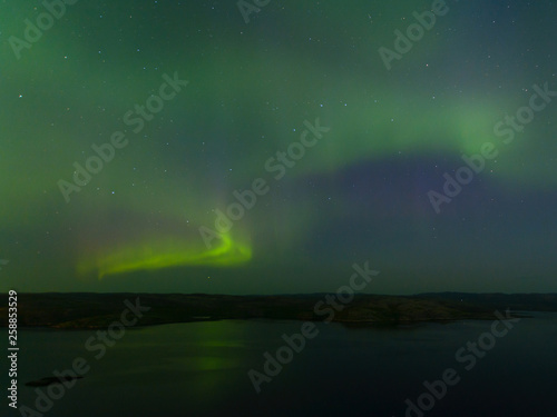 Green northern lights over the water, reflection, aurora. © Moroshka