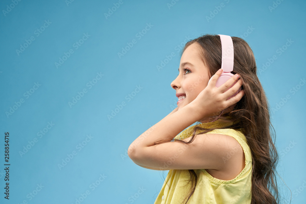 Side view of positive girl in headphones enjoying music