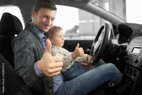 Caring father sitting with son in new comfortable auto