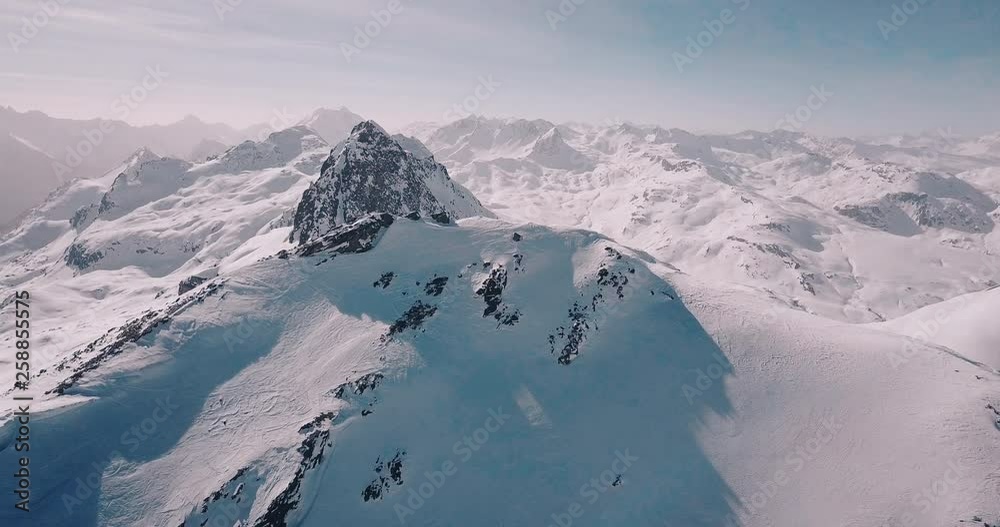 Aerial, decreasing, drone shot, around a snowy alpine mountain, overlooking lots of wintry alp peaks, on a sunny, winter day, in the swiss alps, in Switzerland