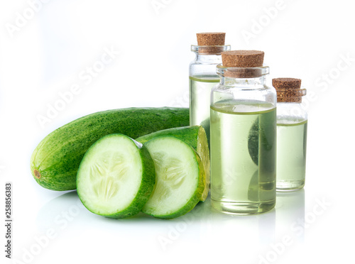 Cucumber slices with cucumber essential oil in glass bottle on white background