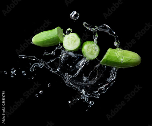 Sliced cucumber with splashing water or explosion flying in the air isolated on black background